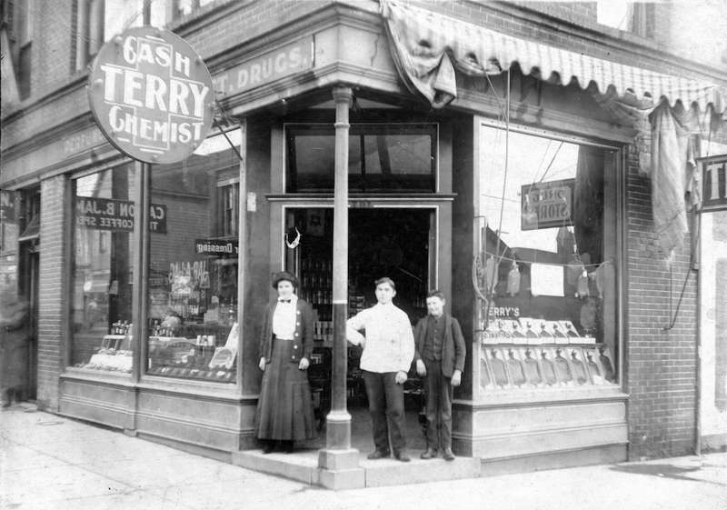 1910-Bert A. Emery [standing with two other people in the entrance of Terry's Drug Store]