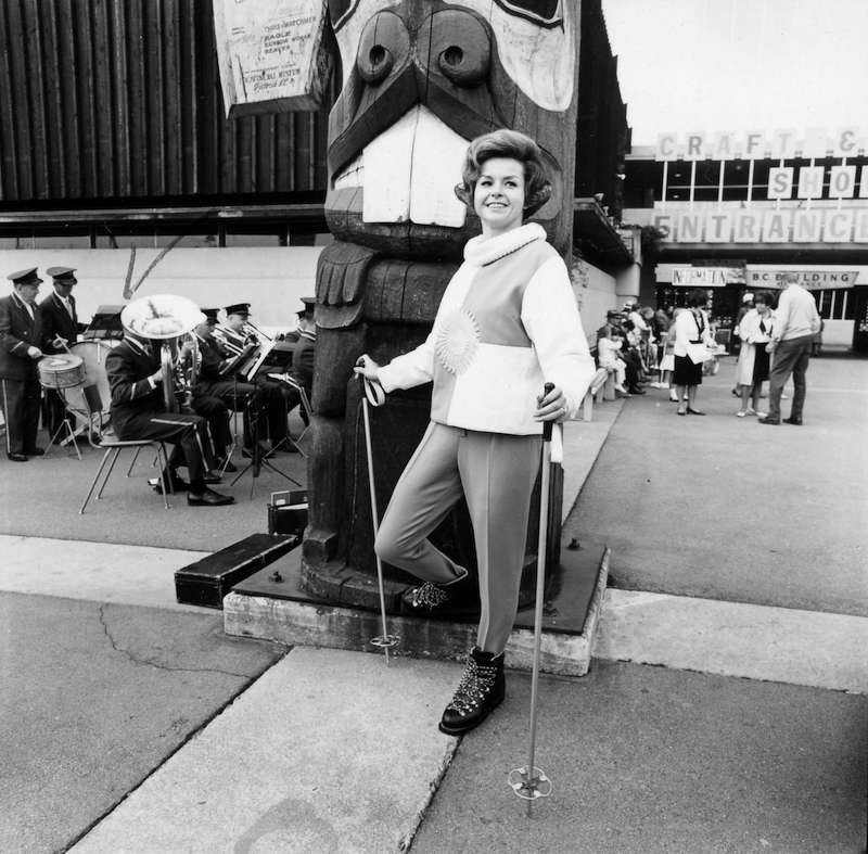 1964 - Fashion show model posing next to P.N.E. B.C. Building