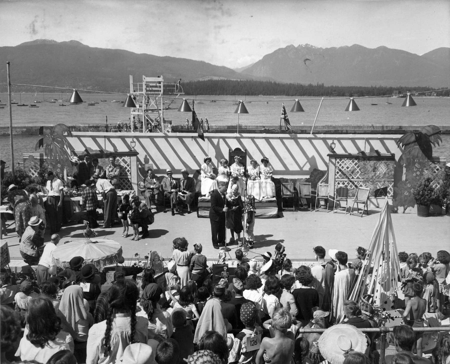 1948 - A man speaking to clowns and other activities on stage in front of Kitsilano Pool for Kitsilano Day