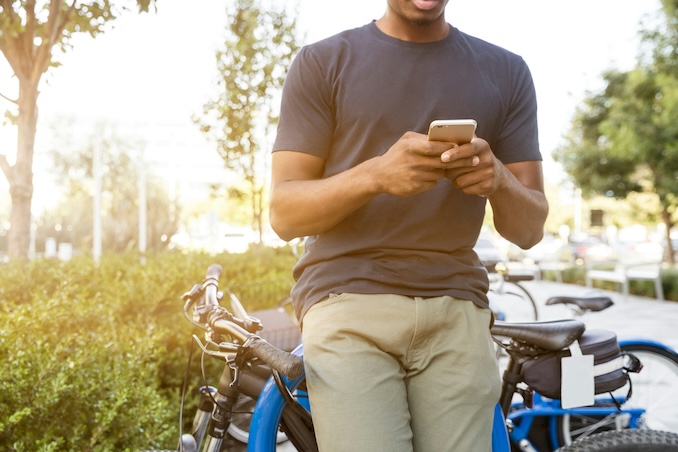 Guy leaning against his bike using his cellphone.