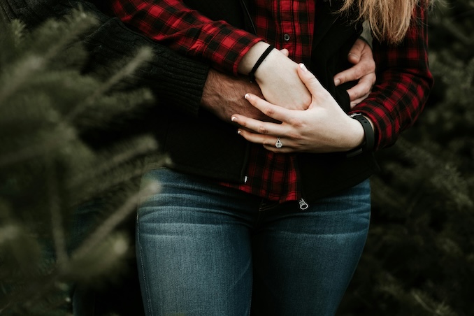 Man hugging woman with engagement ring.