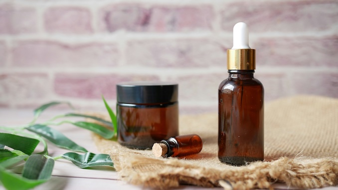 Herbal remedies in glass vials with plants in background.